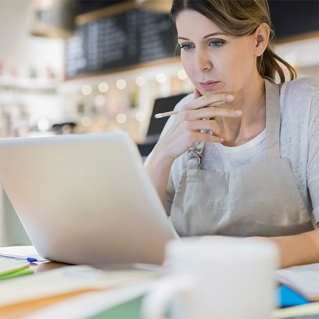 woman looking at laptop screen in cafe